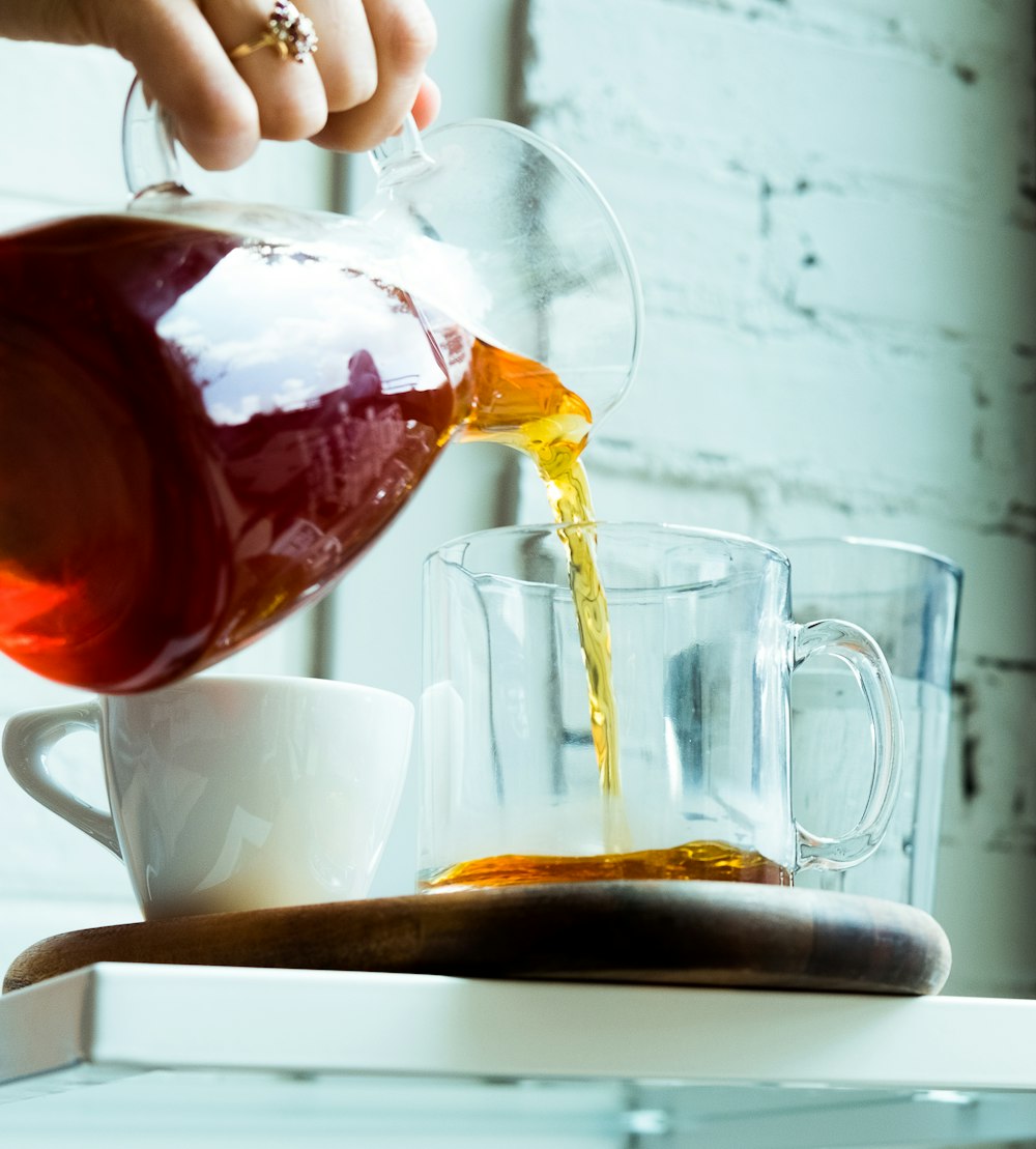 person pouring tea on cup