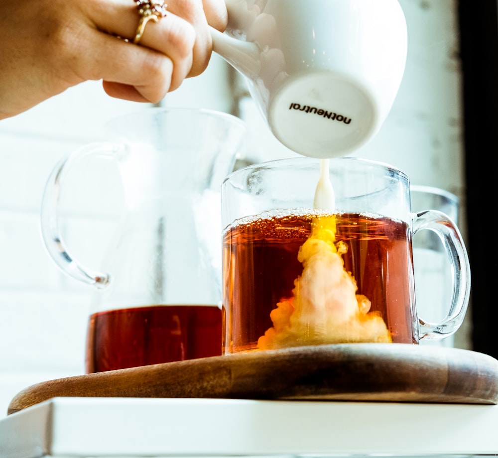 person pouring milk in tea