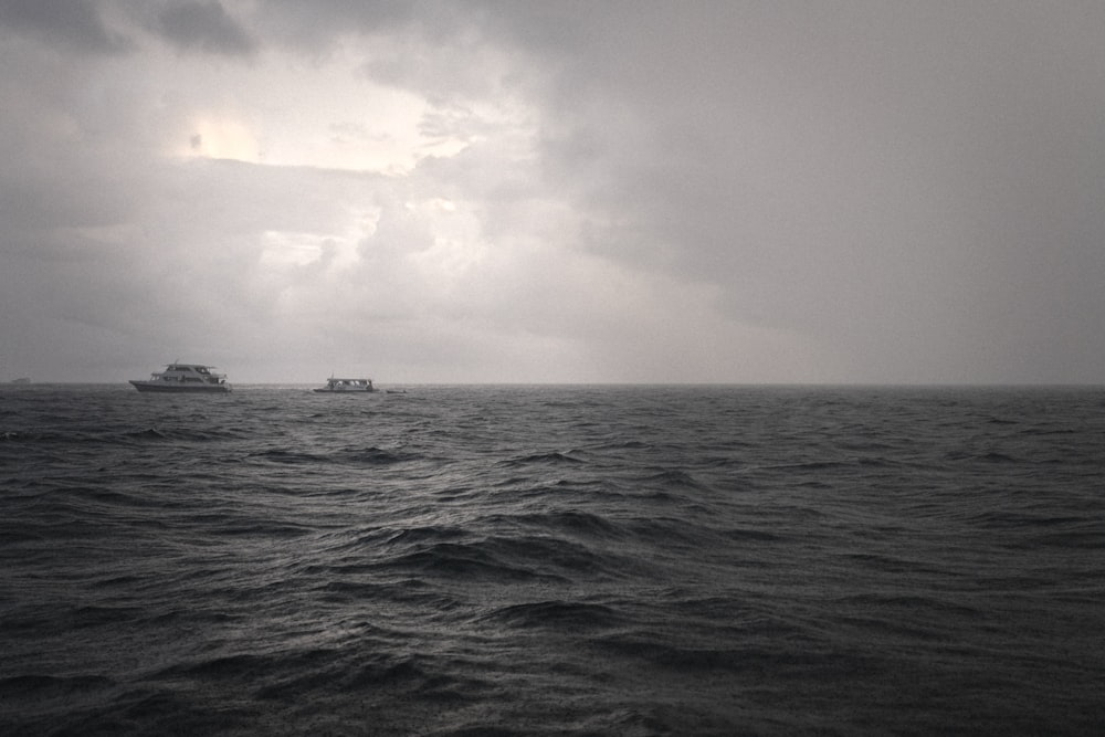 barco en una gran masa de agua en una foto en escala de grises