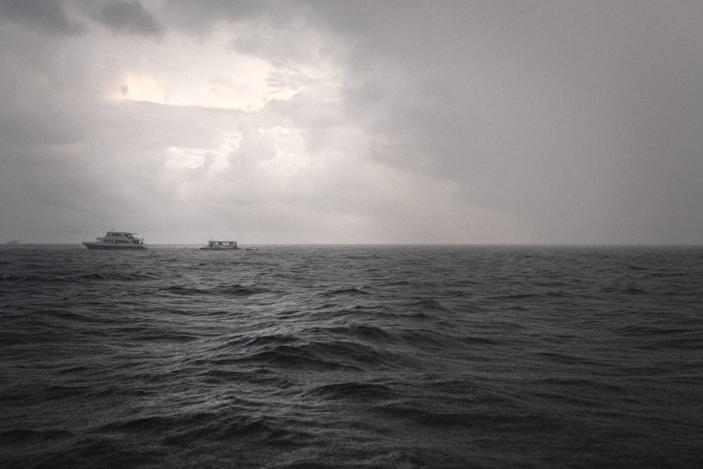 boat on large body of water in grayscale photo