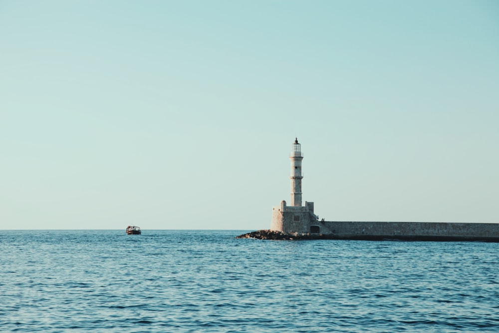 white and gray lighthouse surrounded by body of water under blue sky at daytime