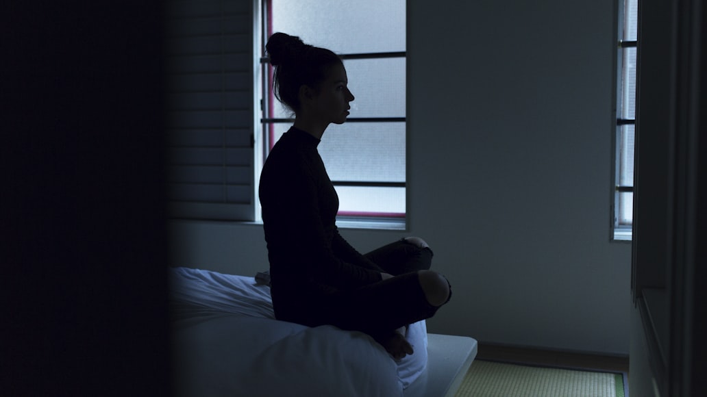 Woman sitting at the side of the bed.
