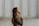 woman in brown long-sleeved top standing beside wall