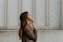 woman in brown long-sleeved top standing beside wall