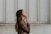 woman in brown long-sleeved top standing beside wall