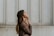 woman in brown long-sleeved top standing beside wall
