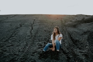 woman sitting on black sand during daytime