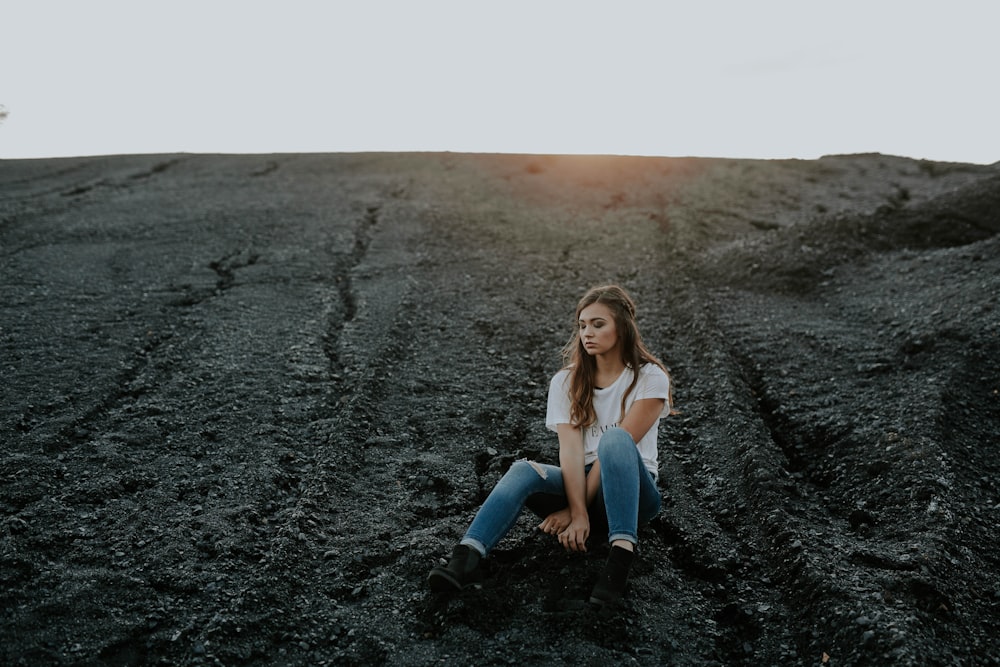 woman sitting on black sand during daytime