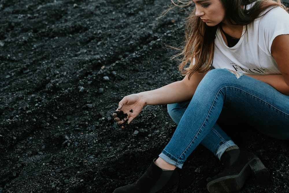 Donna che si siede sul suolo con jeans denim e camicia bianca