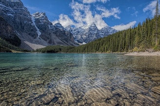 A crystal-clear lake reflecting towering snow-capped peaks at dawn.