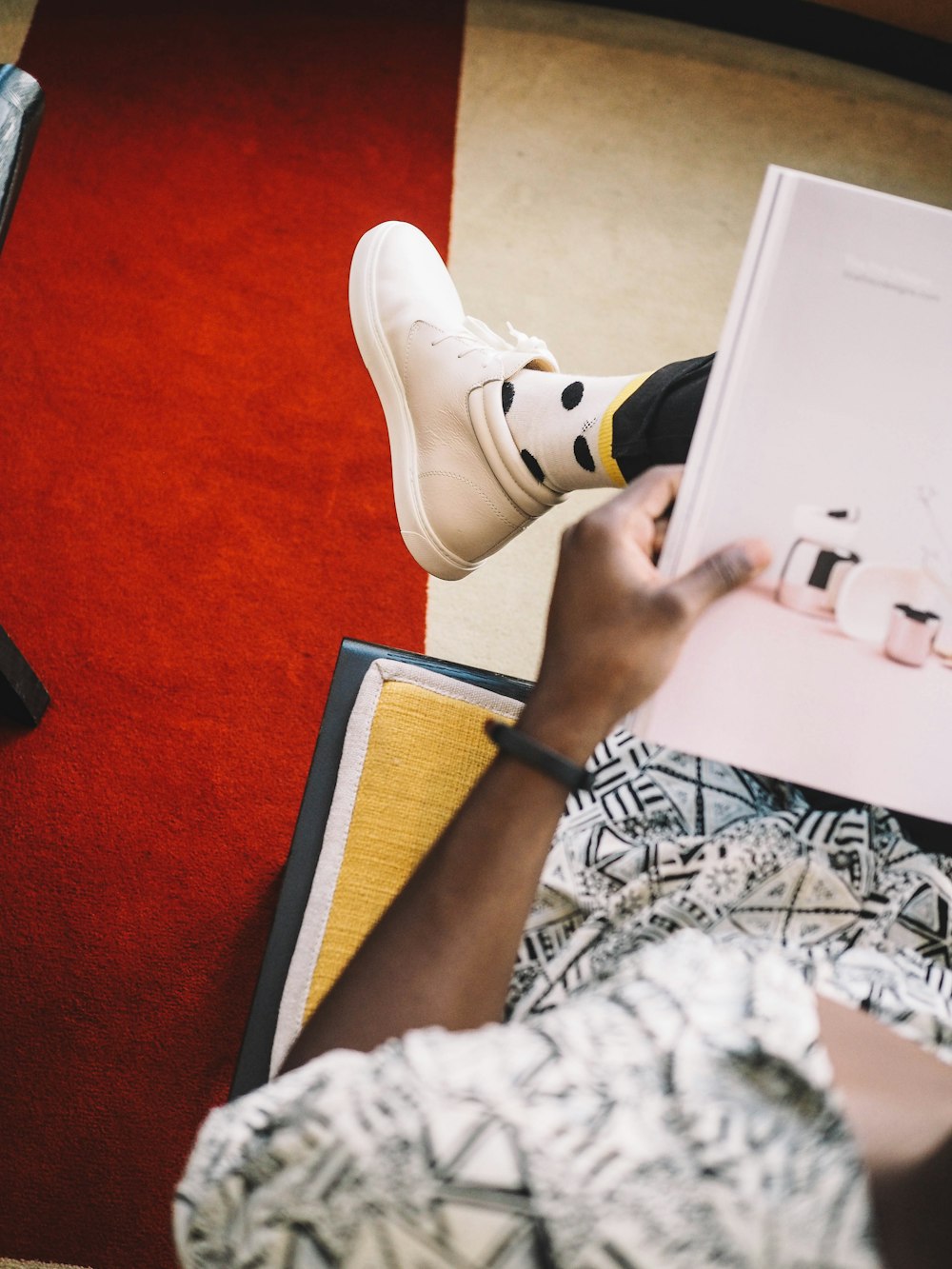 person holding book sitting on orange chair