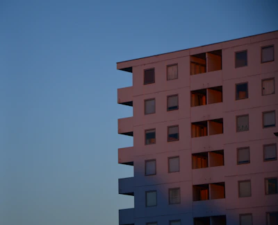 A pristine minimalist residential building with clean lines and large glass windows under soft twilight.