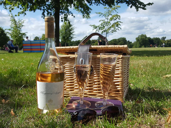 Close-up of a picnic basket filled with local delicacies and a glass of wine on a garden table.