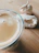 Close-up of a frothy coffee cup next to a flaky, golden pastry on a wooden table.