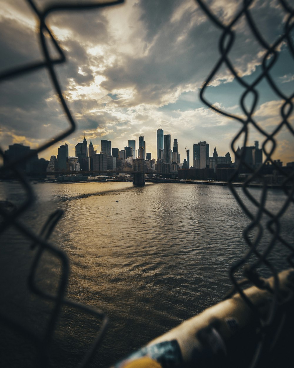 gray fence overlooking body of water far at the city