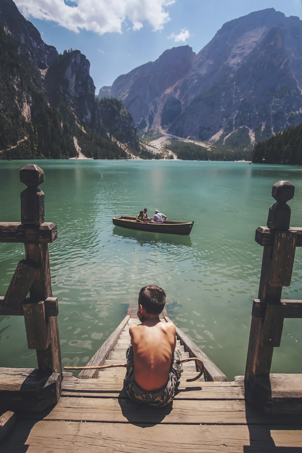 boy sitting on dock during daytime