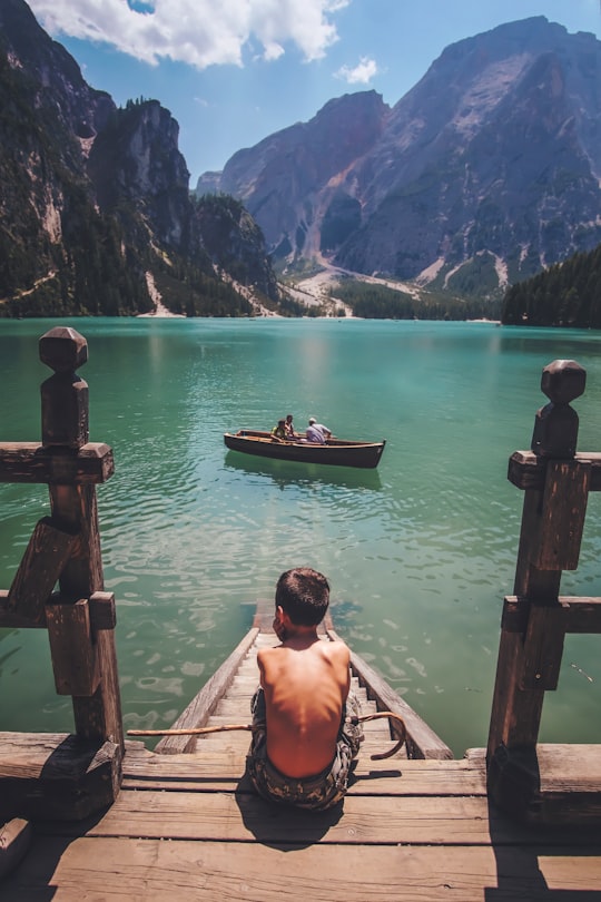 boy sitting on dock during daytime in Parco naturale di Fanes-Sennes-Braies Italy