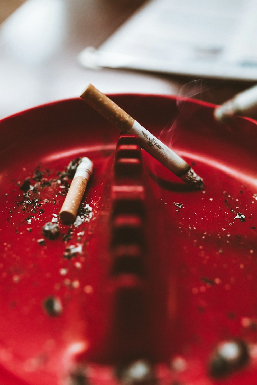 shallow focus photo of white cigarette stick on red ashtray