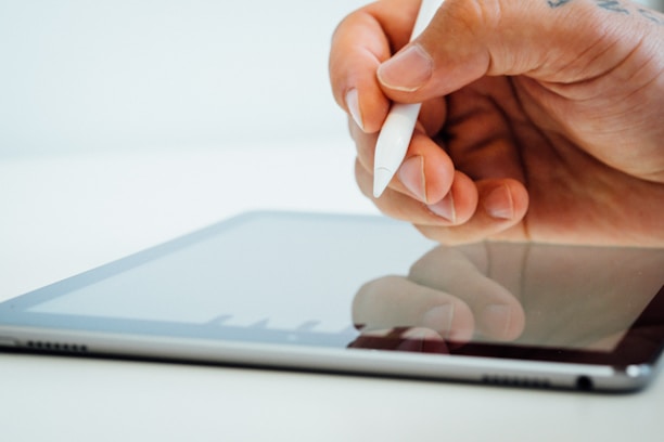 Close-up of hands typing on a tablet with a sleek app interface visible.