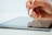 A hand holding a stylus pen above a tablet screen, poised for interaction. The focus is on the fingers gripping the stylus and the sleek surface of the tablet.