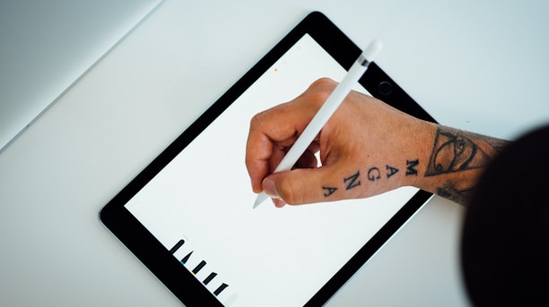 person holding white stylus writing on black iPad