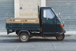 A vintage Piaggio Ape decorated with traditional Sicilian cart motifs, parked in a sunny Aix-en-Provence street.