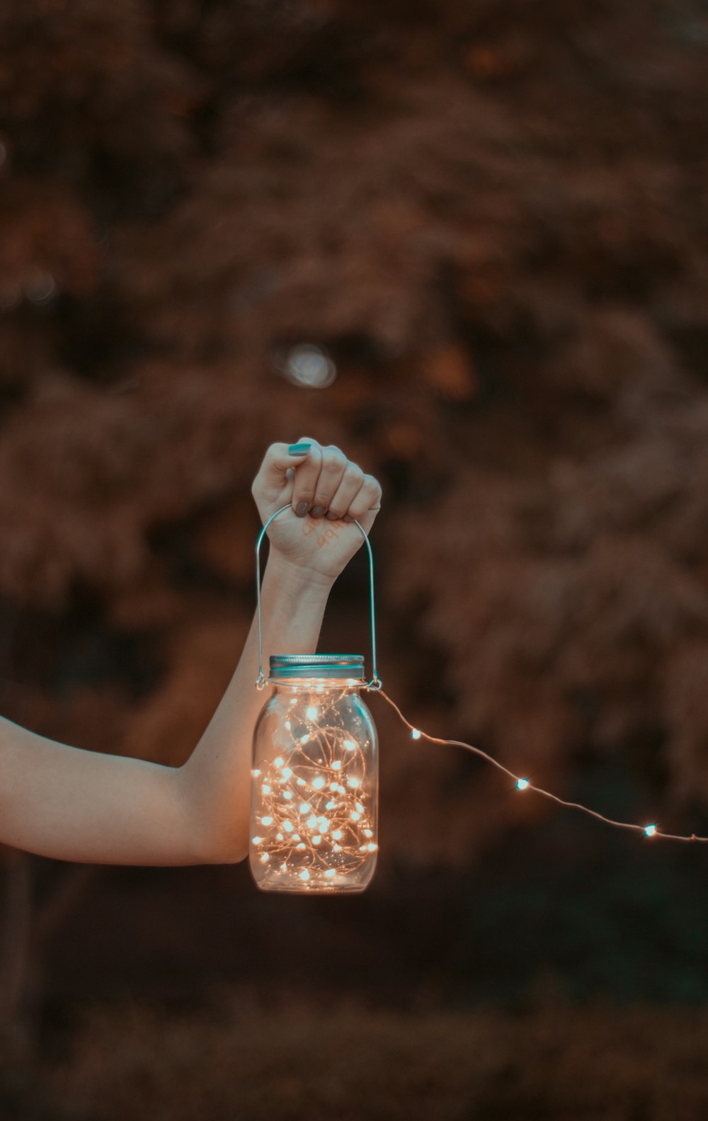 Persona sosteniendo un frasco de vidrio con luces de cadena