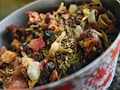 A close-up view of a bowl filled with a variety of dried herbs, fruits, and flowers. The mixture includes visible ingredients like rose petals, dried berries, and pieces of dehydrated fruit and leaves, creating a rich textural composition.