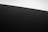 A minimalistic photograph capturing a sand dune with fine ripples under natural light. The horizon is slightly angled, creating a dynamic composition. The sky is clear and the sand appears almost black.