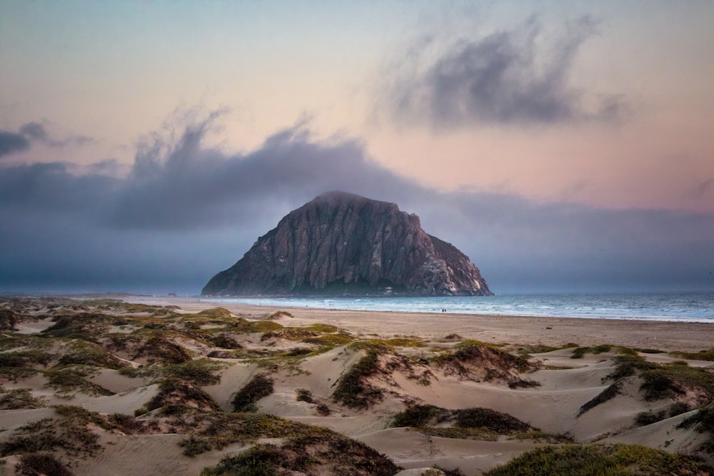 Foto di paesaggio di montagna marrone circondata da uno specchio d'acqua vicino alla riva del mare