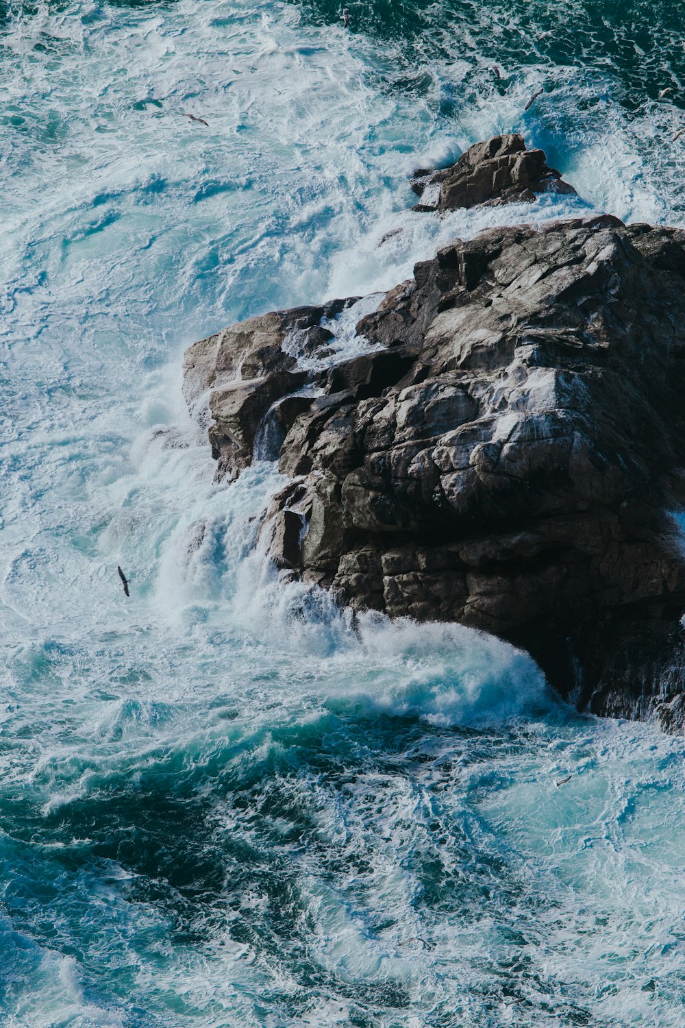 Fotografía aérea de la ola del mar salpicando en la roca