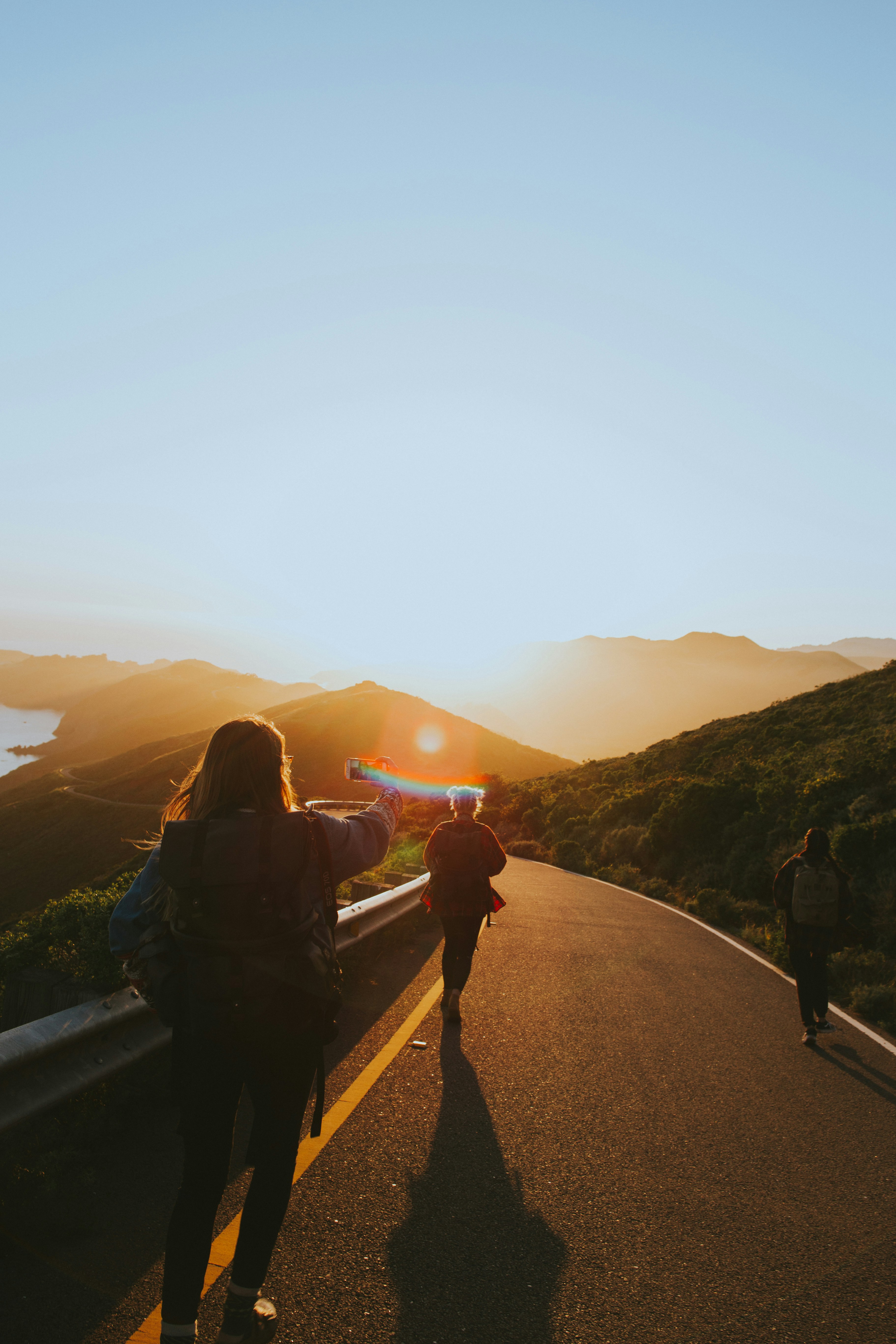 group of people walking towards gray asphalt road during orange sunset low-light photography