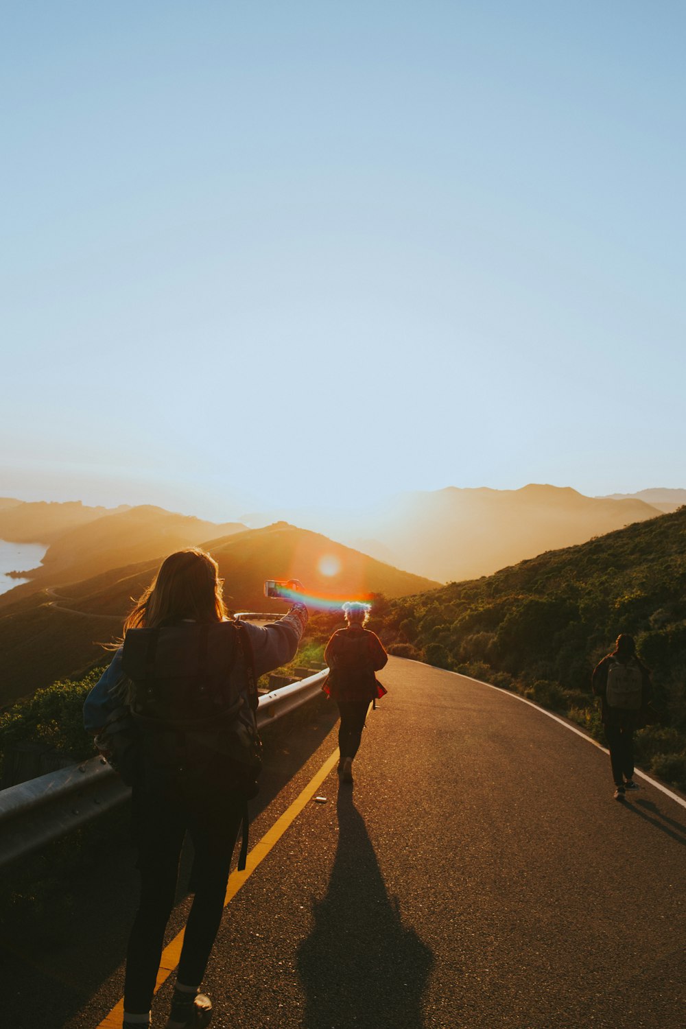 group of people walking towards gray asphalt road during orange sunset low-light photography