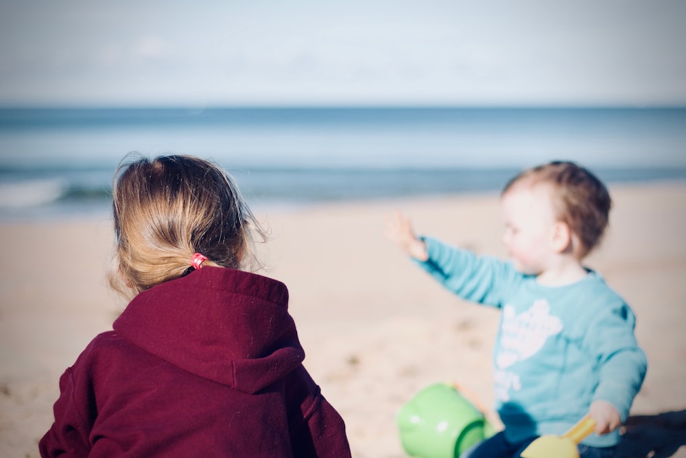 Dos niños pequeños sentados en la orilla del mar