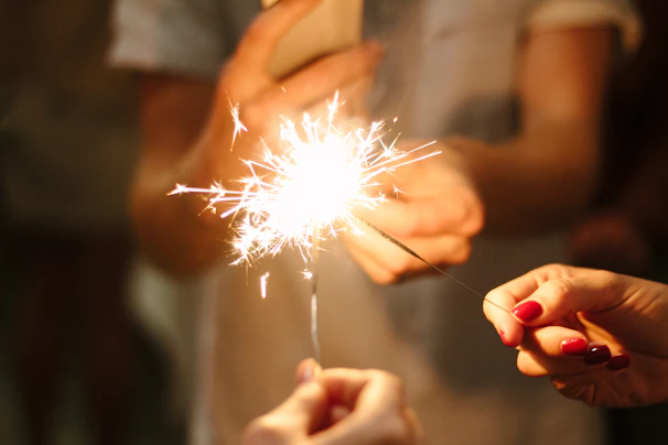 Close-up of sparklers glowing warmly in someone's hand.