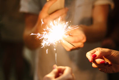 Close-up of hands carefully handling a sparkler with a warm glow