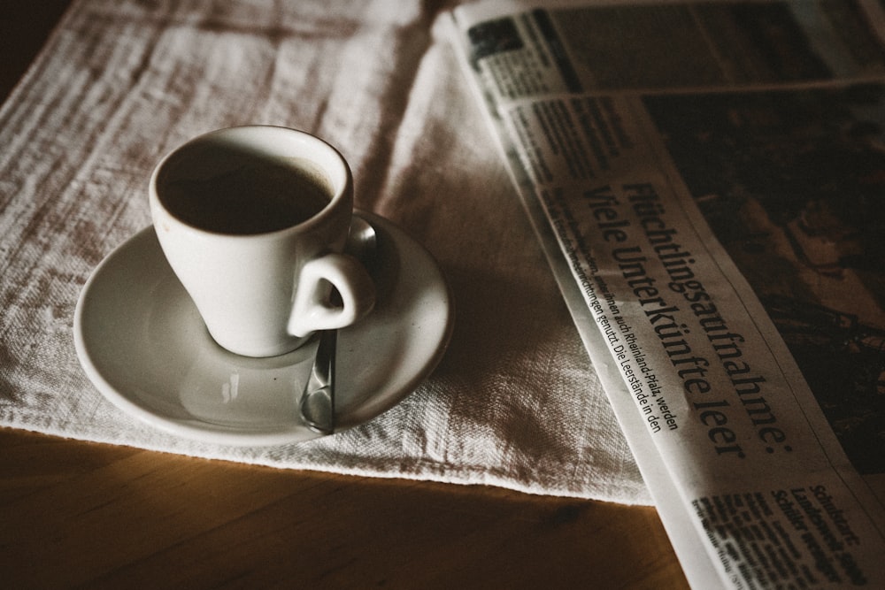 taza de té en platillo cerca del periódico