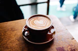 Cozy cafe corner with soft lighting, wooden furniture, and a latte art heart in a ceramic mug.