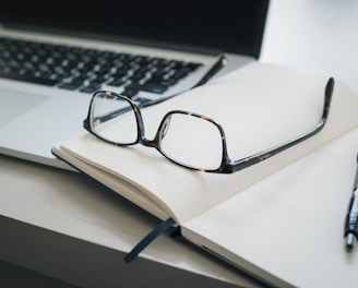 black framed eyeglasses and black pen