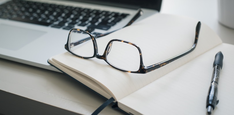 black framed eyeglasses and black pen