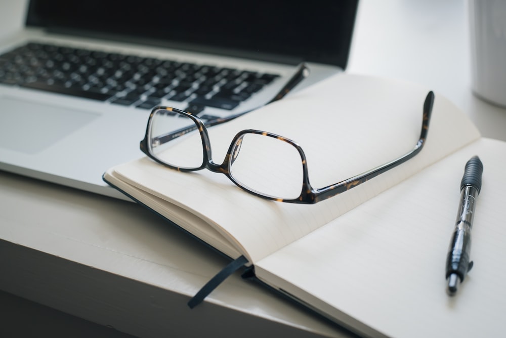 black framed eyeglasses and black pen