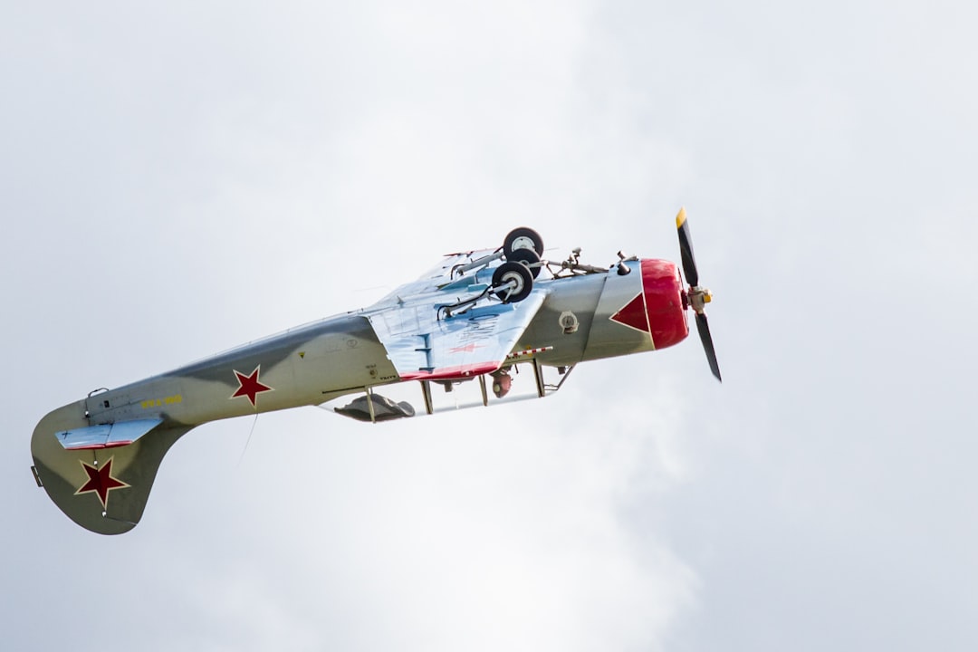 gray and red airplane making a stunt