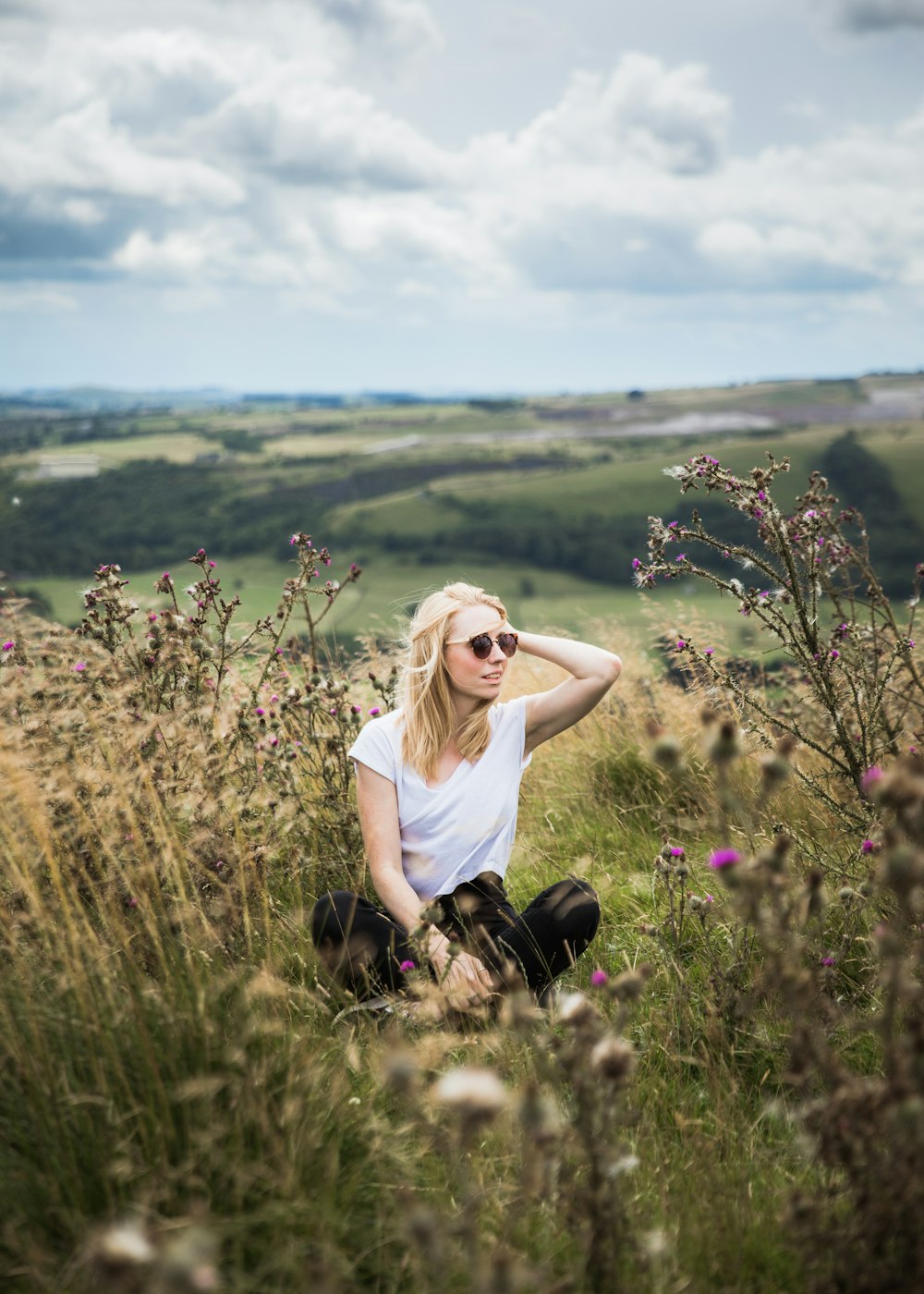 selective focus of woman sitting on green grass in an open field at daytime