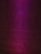 Close-up of cracked concrete casting sharp shadows under dim neon violet glow.