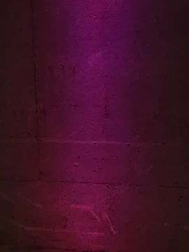 Close-up of cracked concrete casting sharp shadows under dim neon violet glow.