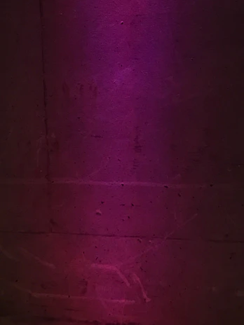 Artistic projection mapping in rich purple hues illuminating a textured wall in a dark room.