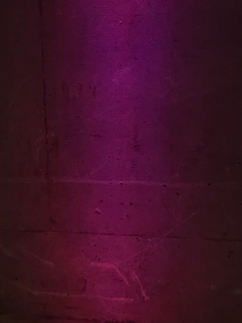 Modern interior wall with smooth cement finish and vibrant purple accents.