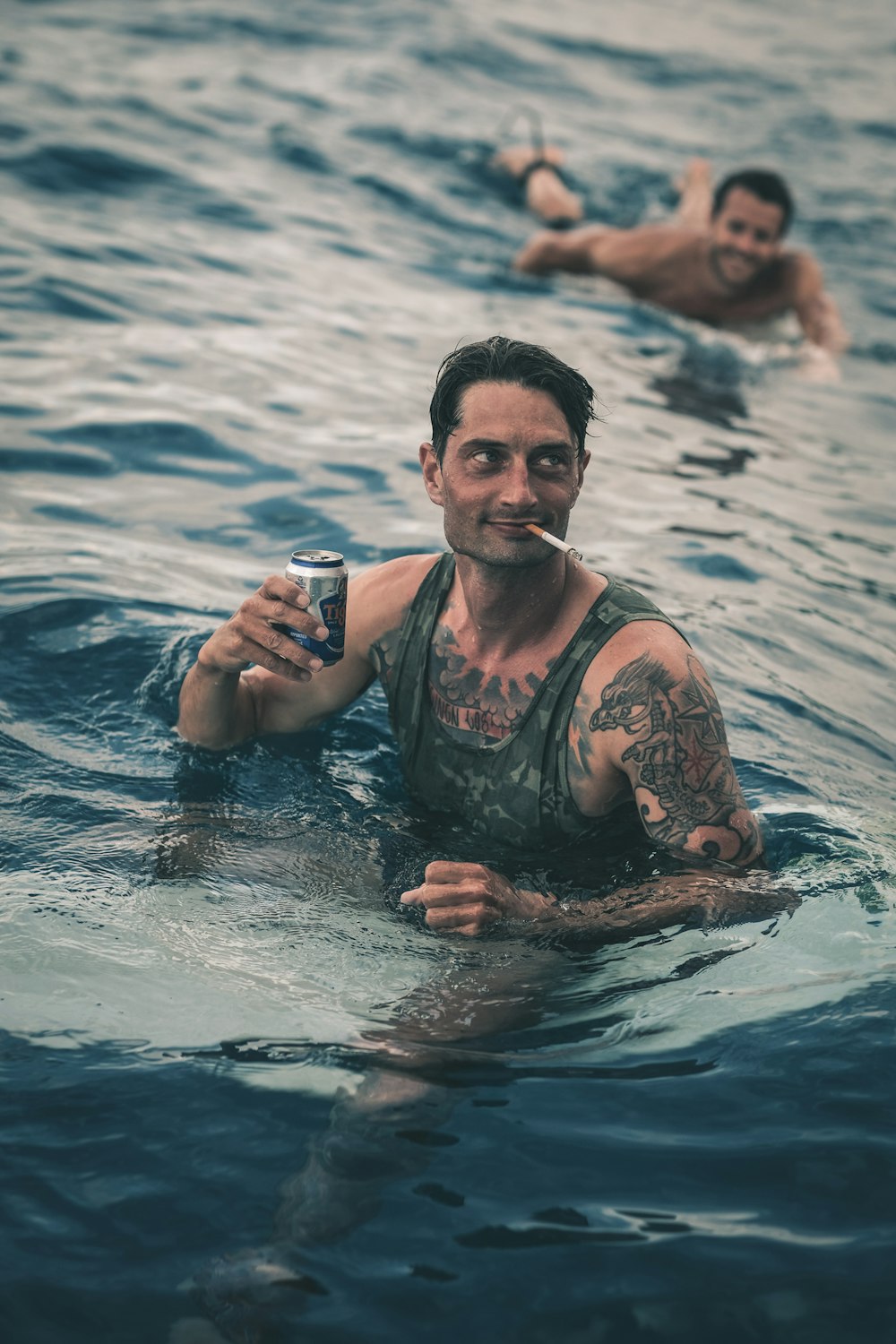 man holding can while smoking on sea at daytime