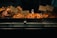 A display of various roasted foods including rotisserie chicken, roasted potatoes, roast cauliflower with harissa, and roasted carrots with yogurt and tahini. Each dish is separated into metal trays with signs indicating their names and descriptions.