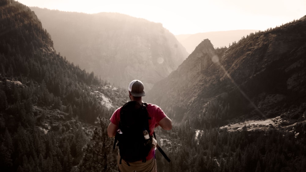 man standing on elevated ground facing mountains during daytime